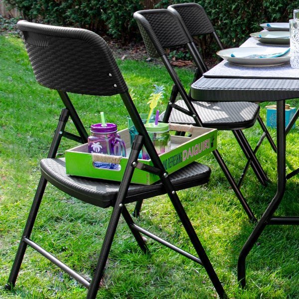Gartenszene mit einem Tisch und mehreren schwarzen Klappstühlen im Freien