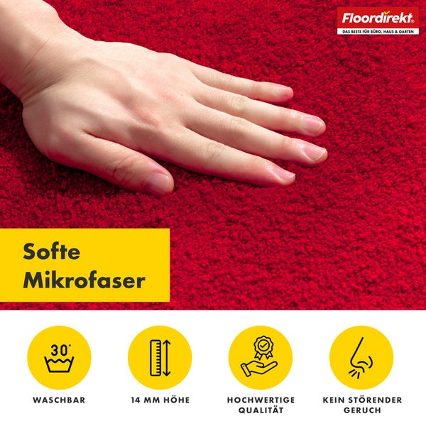Detailaufnahme eines roten Teppichs mit weicher Mikrofaserstruktur und einer Hand, die die Oberfläche berührt. Waschbar bei 30 Grad. 14 Millimeter Höhe. Hohe Qualität. Kein störender Geruch. Floor direkt Logo.