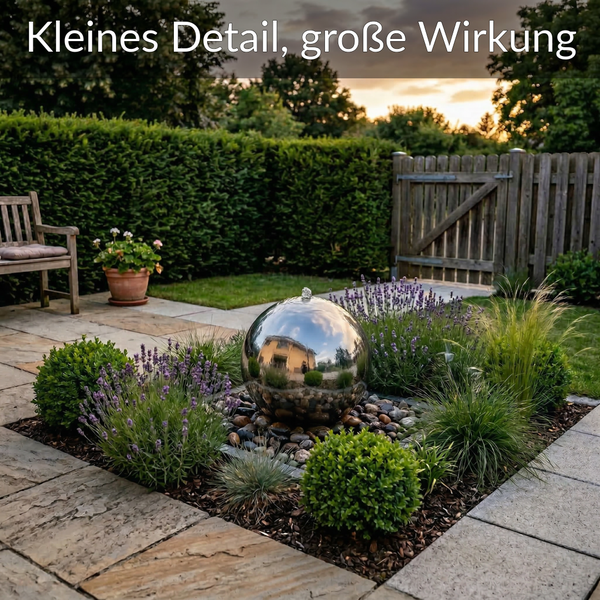 Edelstahl-Kugelbrunnen in einem organisierten Gartenbeet mit Lavendel und Gräsern auf einer Terrasse aus Natursteinplatten.