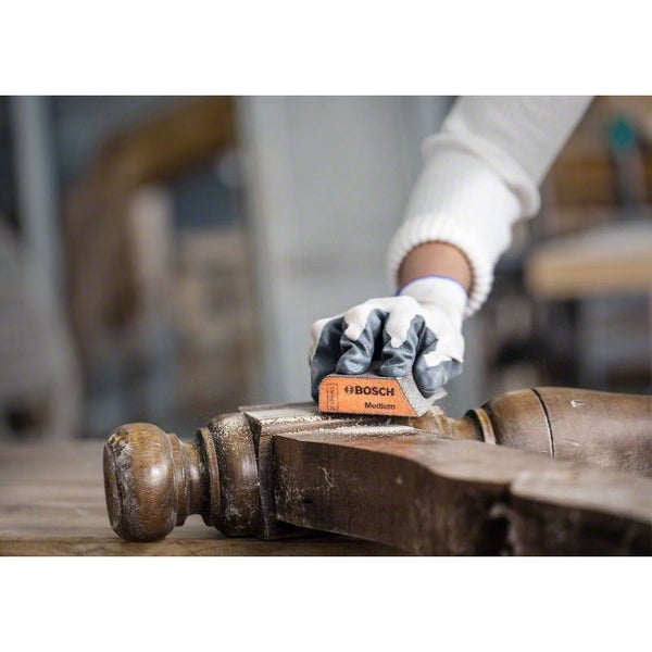Eine Person schleift ein Holzobjekt mit einem Schleifpad von Bosch