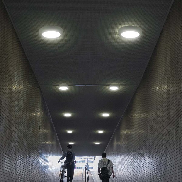 Unterführung mit runden Deckenleuchten und Passanten