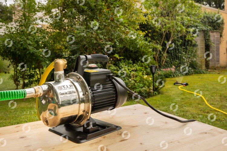 Gartenpumpe auf einem Holztisch im Garten mit Rasensprenger