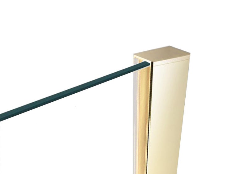 Detailansicht einer Duschwand aus Glas, die in ein goldfarbenes Wandprofil eingefasst ist.