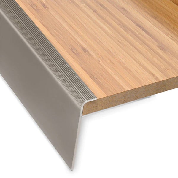 Treppenkantenprofil aus Metall mit gerippter Oberfläche an einer Holzstufe für Rutschfestigkeit und Kantenschutz.