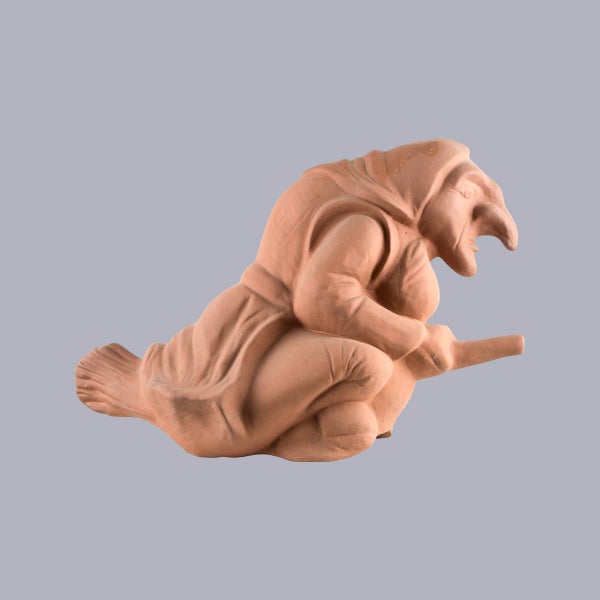 Firstfigur Hexe aus Terrakotta auf einem Besen reitend zur Dekoration des Dachfirsts.