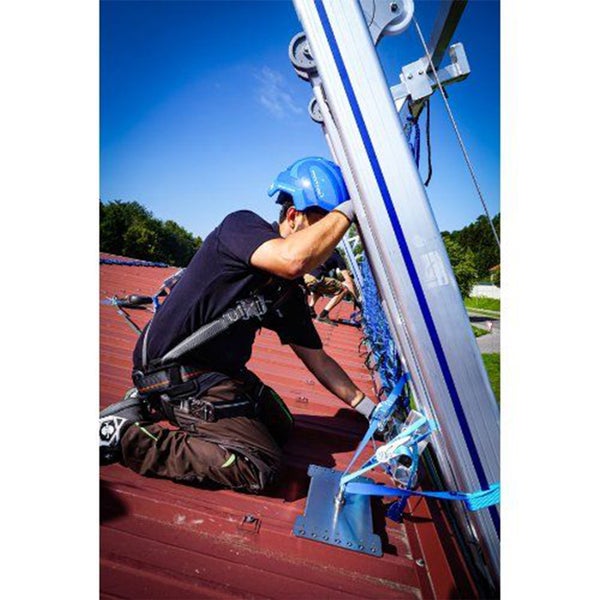 Ein Arbeiter auf einem Dach mit einer Absturzsicherung montiert ein Sicherheitssystem.