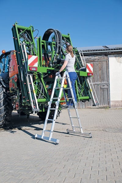 Person steht auf einer multifunktionalen Aluminium Gelenkleiter bei Wartungsarbeiten an einer landwirtschaftlichen Maschine im Freien
