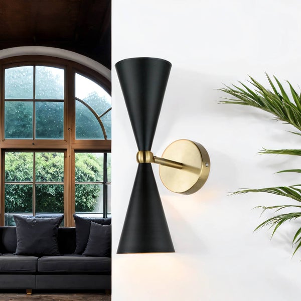 Dekorative Wandleuchte aus Metall in Schwarz und Gold neben einer Zimmerpflanze und einem Sofa