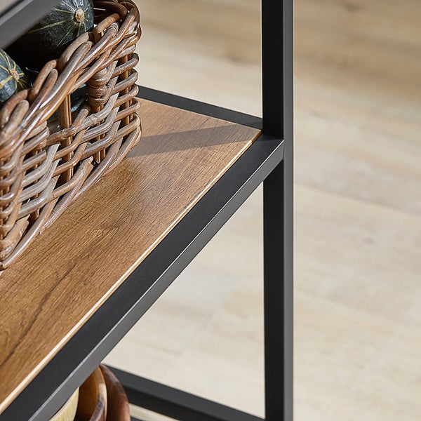 Detailaufnahme eines Regals mit schwarzem Metallrahmen und Holzregalböden, dekoriert mit einem Korb