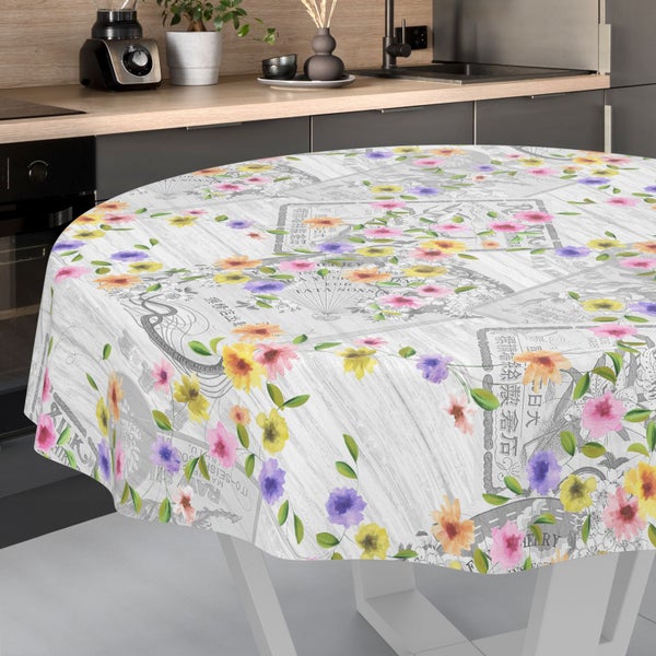 Runde Tischdecke mit Blumenmuster und Vintage-Postkartenmotiven auf einem weißen Esstisch in einer modern eingerichteten Küche.