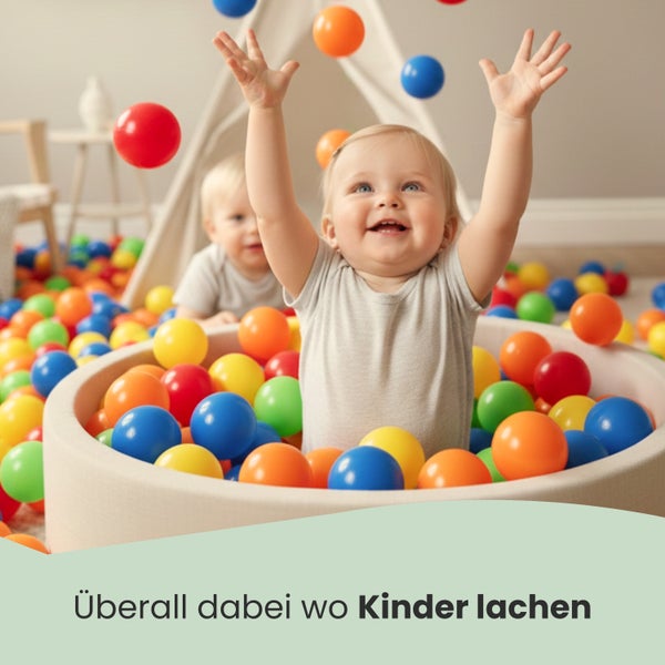 Ein Kind spielt in einem runden Bällebad mit zahlreichen Kunststoffbällen in einem Spielzimmer.
