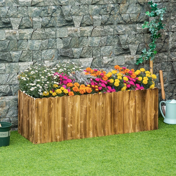 Holzhochbeet mit Blumen und Gartengeräten vor Steinwand