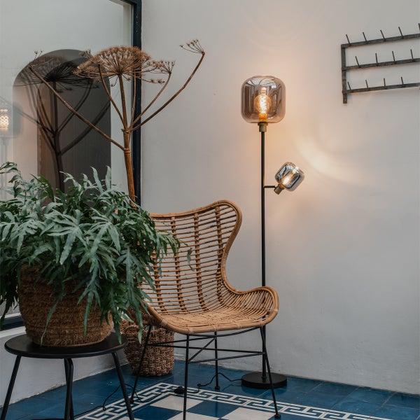 Szene mit Korbstuhl, Stehlampe und Pflanze