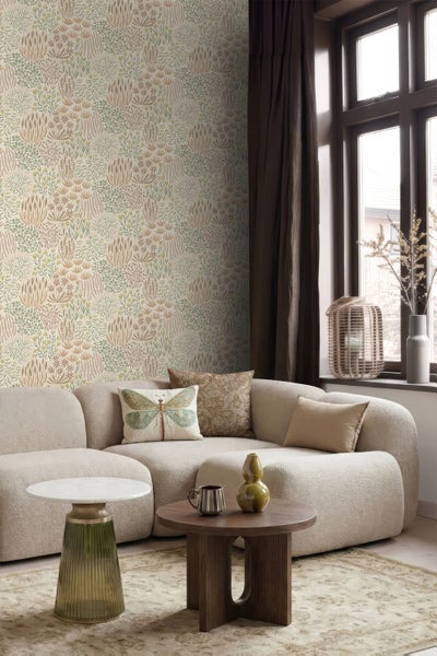 Helle Vliestapete mit abstraktem Naturmuster in einem modern eingerichteten Wohnzimmer mit geschwungenem Sofa und Couchtisch.