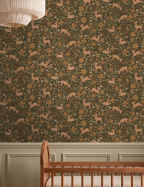 Tapete mit Reh und Blumen Muster in einem Kinderzimmer über einem hölzernen Kinderbett