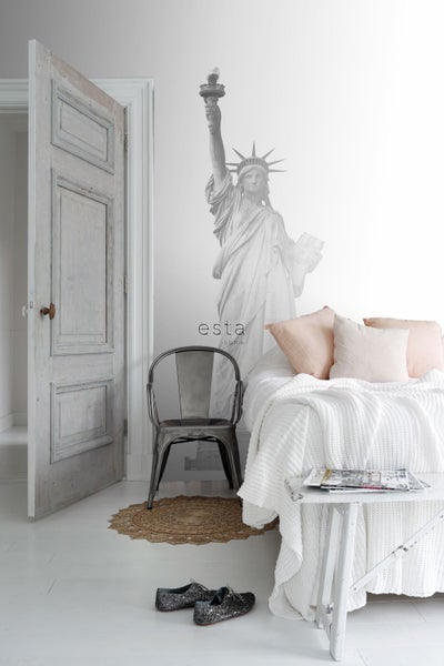 Helles Schlafzimmer mit Bett, Stuhl, Wandbild Freiheitsstatue und offen stehender Tür