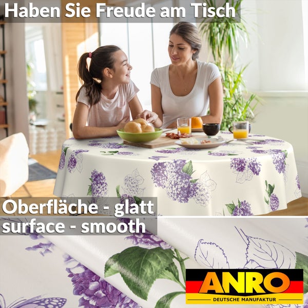 Runde Tischdecke mit glatter Oberfläche und violettem Hortensienmuster. Szene zeigt Frau und Kind an einem gedeckten Tisch. ANRO Logo.
