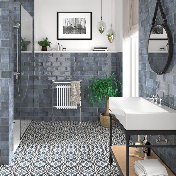 Modernes Badezimmer mit blauen Wandfliesen im Backsteindesign, gemusterten Bodenfliesen, offener Dusche und einem Waschtisch mit weißem Becken.