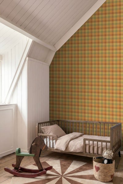 Kinderzimmer mit karierter Tapete an einer Dachschräge, einem hölzernen Kinderbett und einem Schaukelpferd auf einem Holzboden.