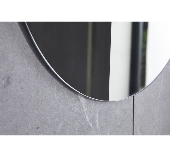 Detailaufnahme eines runden Spiegels an einer grauen Marmorwand