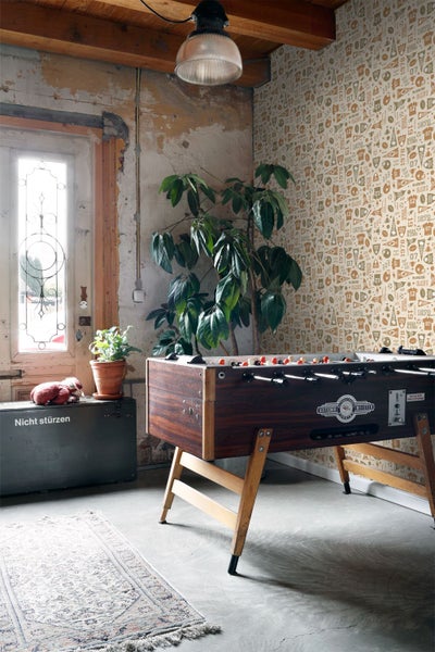 Innenraum mit Fussballtisch, Pflanze und dekorativer Tapete