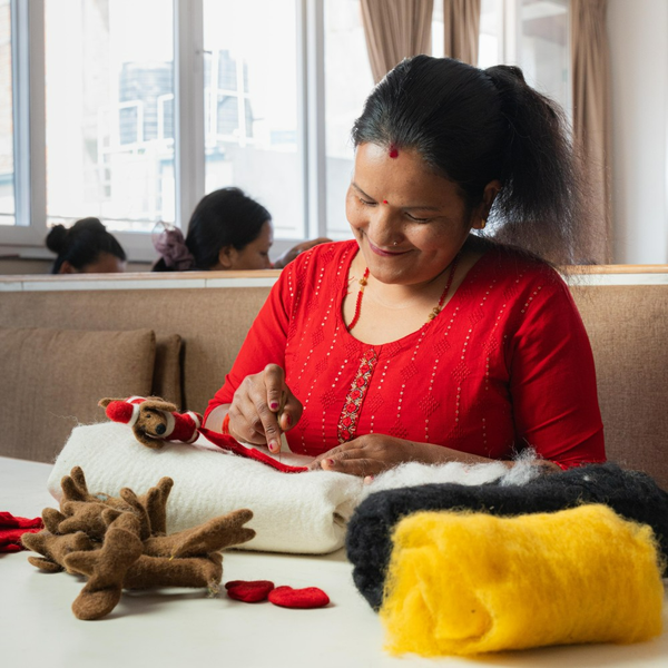 Eine Frau näht ein Filzprodukt in einer hellen und organisierten Umgebung.