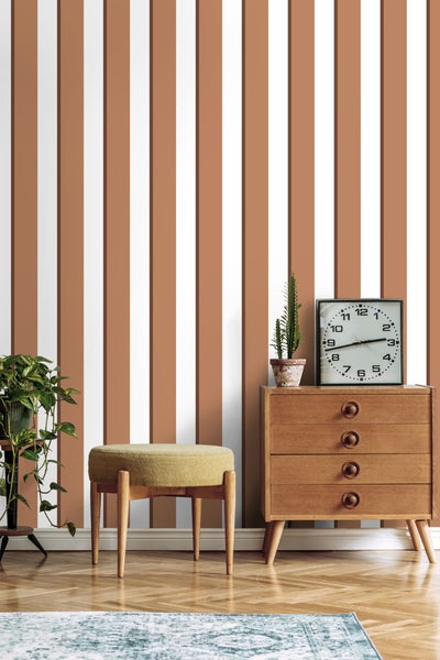 Raumansicht mit gestreifter Tapete, Kommode, Hocker und Topfpflanzen für eine gemütliche Atmosphäre.