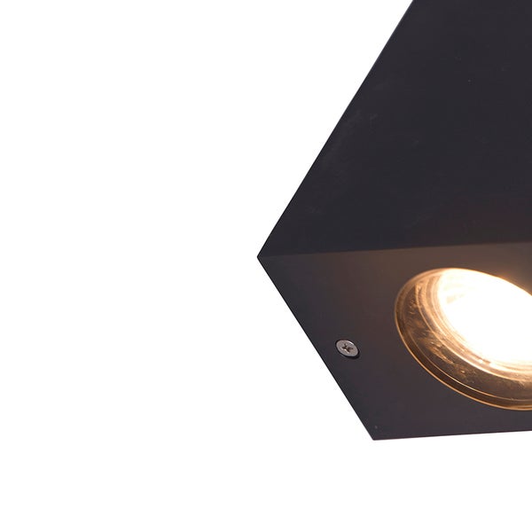 Nahaufnahme einer schwarzen quaderförmigen Wandlampe mit leuchtendem Leuchtmittel.
