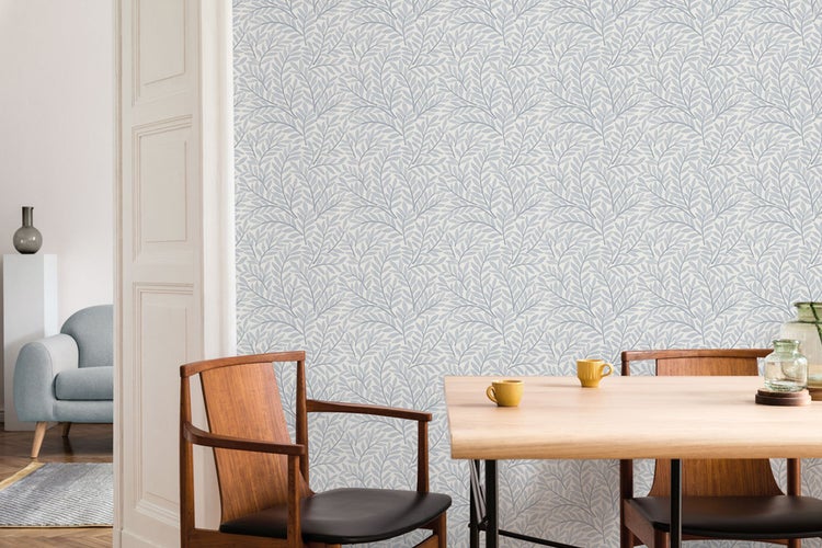 Esszimmer mit Tapete mit Blattmuster, Holztisch und Stühlen.