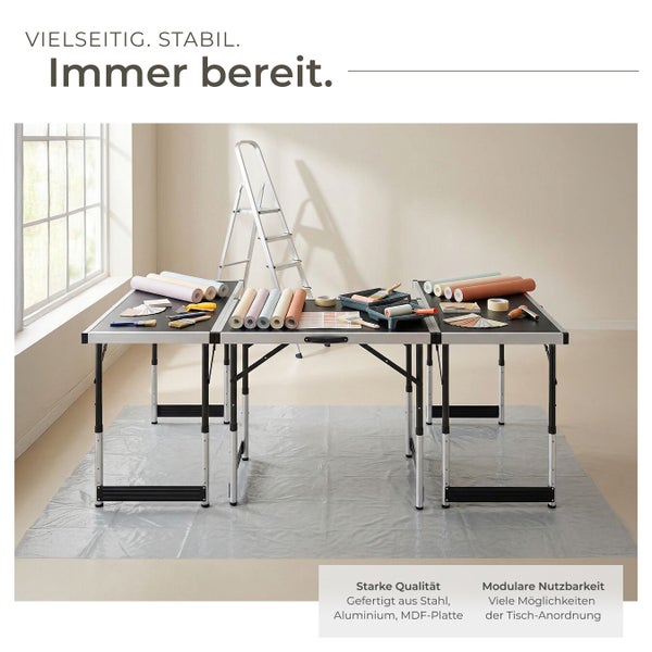 Szene mit Malervliestuch, zwei Tapeziertischen, einer Leiter und Malermaterialien