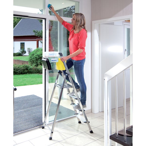 Frau reinigt Fenster stehend auf einer Trittleiter der Marke Krause.