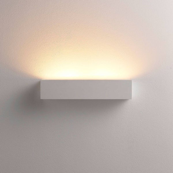 Weiße rechteckige LED-Wandleuchte mit indirektem warmweißem Lichtaustritt nach oben an einer verputzten Wand.