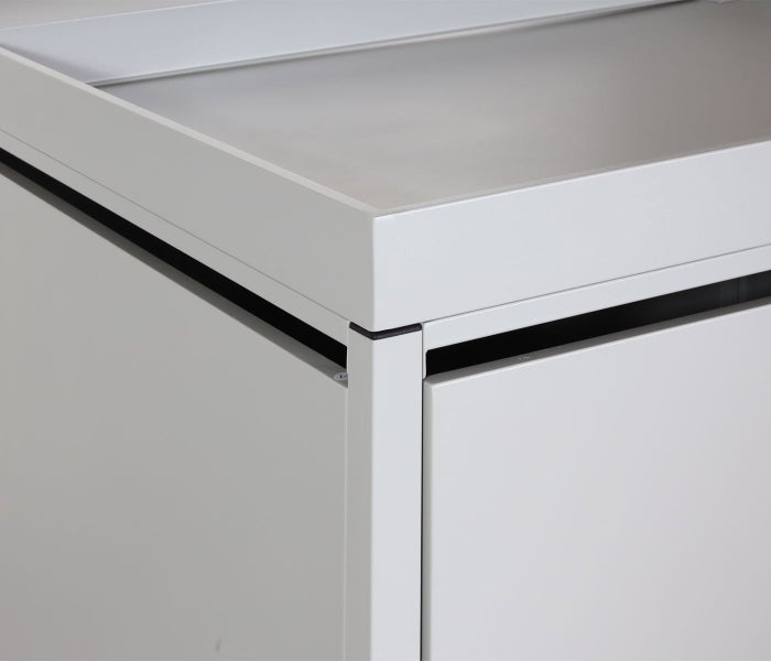 Nahaufnahme einer hellgrauen Metallschrank-Ecke mit vertiefter Oberseite und pulverbeschichteter Oberfläche.