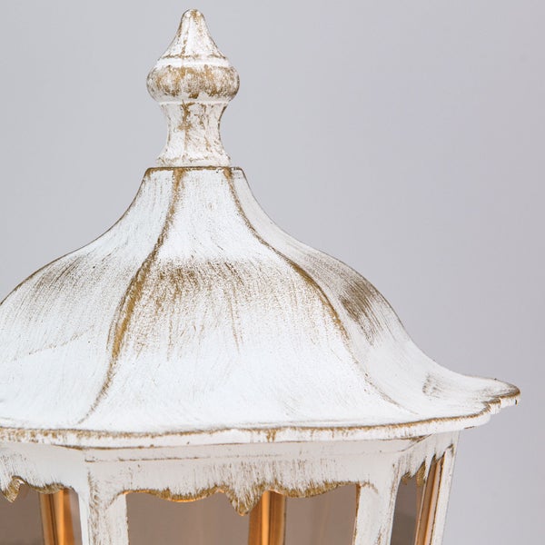 Nahaufnahme der dekorativen Oberseite einer Außenlaterne im klassischen Stil mit weiß-goldener Oberfläche.