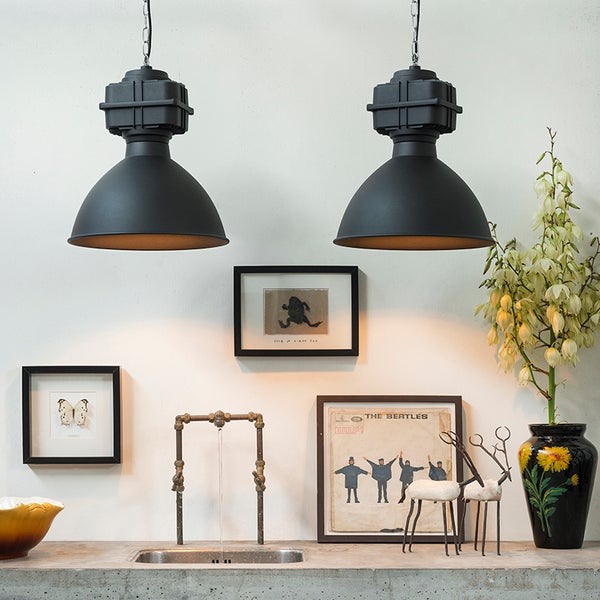 Zwei schwarze Hängelampen im Industriedesign über einer Arbeitsfläche mit Dekorationen