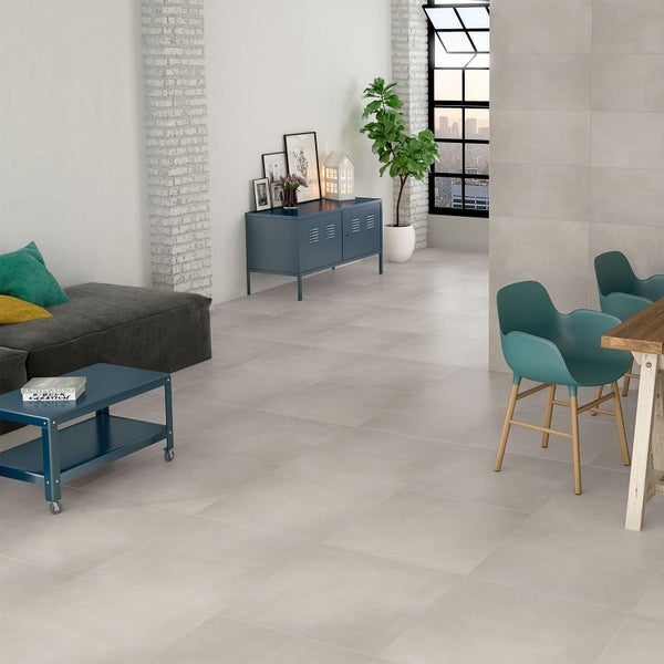 Modernes Wohnzimmer mit großformatigen grauen Bodenfliesen in Betonoptik, weißer Ziegelwand, blauem Sideboard und teal-farbenen Stühlen.