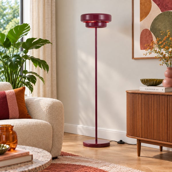Moderne Stehlampe mit rundem Lampenschirm im Wohnzimmer neben Sessel und Sideboard mit Zimmerpflanze.