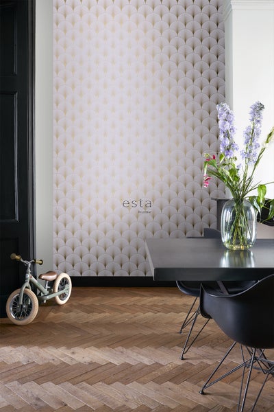 Ein Zimmer mit einer Wandtapete mit einem Fächermuster in Gold, einem Esstisch mit Stühlen und einem Kinderfahrrad.