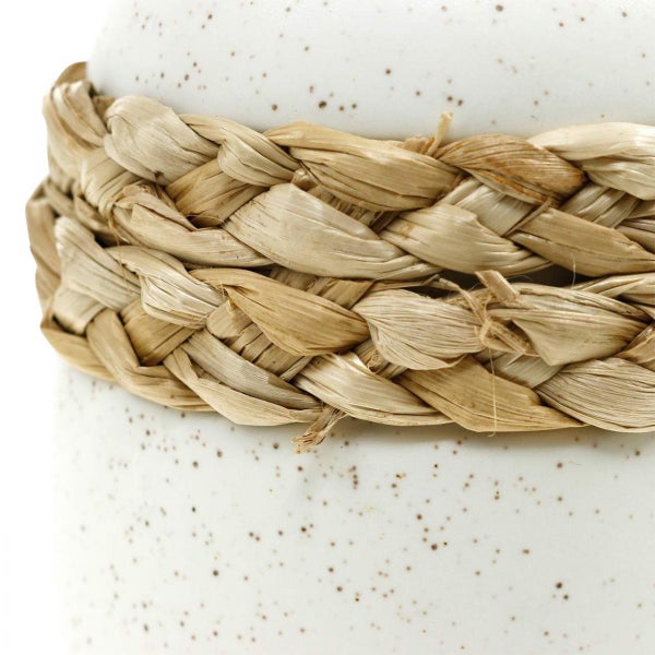 Detailansicht eines gesprenkelten Keramiktopfes mit einem geflochtenen Strohband.