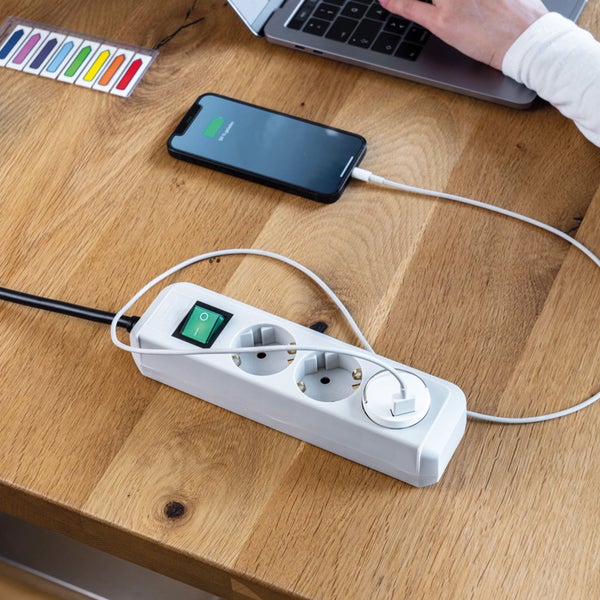 Mehrfachsteckdose mit Schalter auf einem Tisch mit elektronischen Geräten