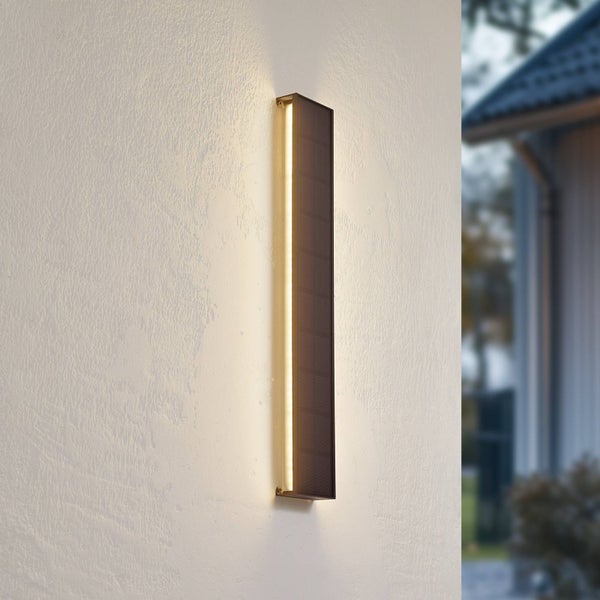 Moderne, bronzefarbene LED-Solar-Wandleuchte in schmaler, rechteckiger Form, vertikal an einer Hauswand montiert.