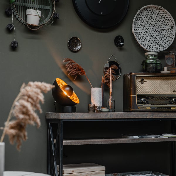 Dekoratives Interieur mit Tischleuchte, Radio und Wanddekorationen auf einem Regal.