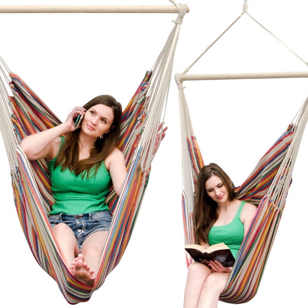 Bunter Hängesessel mit Streifenmuster und Holzstab, Frau telefoniert und liest im Sessel sitzend.