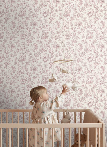 Vliestapete mit feinem Blumenmuster in einem hellen Kinderzimmer hinter einem Gitterbett aus Holz.