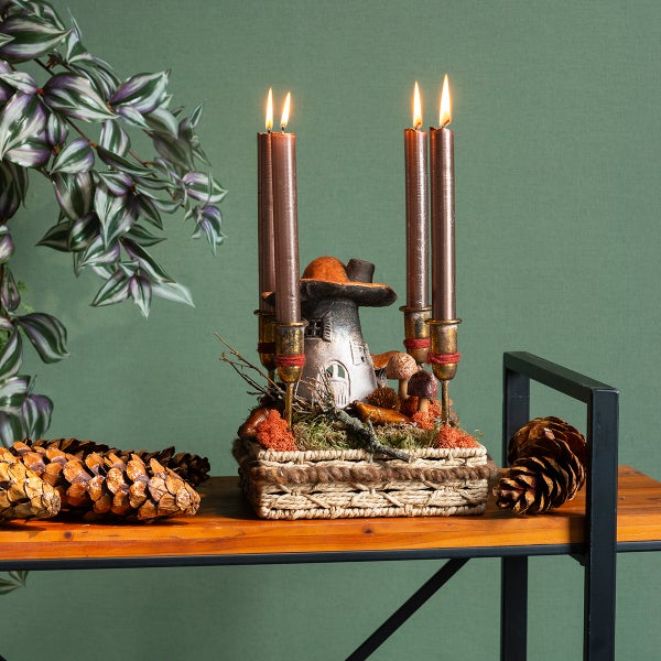 Dekorative Pilzhaus Kerzenhalter mit brennenden Kerzen in einem geflochtenen Korb auf einem Regal