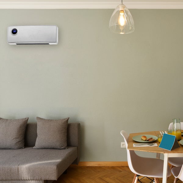 Wohnzimmer mit Sofa, Esstisch und einem an der Wand montierten Heizgerät.