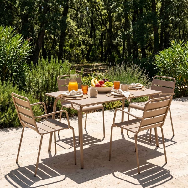 Moderne Garten-Essgruppe aus beige lackiertem Metall mit rechteckigem Tisch und vier Armlehnstühlen auf einer sonnigen Terrasse.