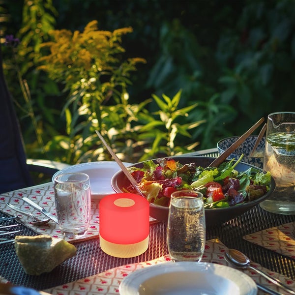 Wetterfeste LED Außenleuchte mit Schutz gegen Spritzwasser auf einem Tisch im Regen, tragbare Tischleuchte für Terrasse und Garten.