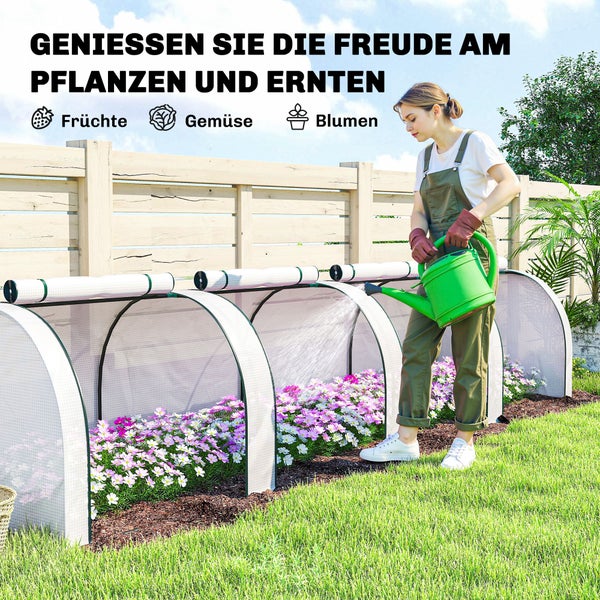 Eine Frau gießt Blumen in einem Garten mit einem Foliengewächshaus-Tunnel mit aufrollbarer Abdeckung vor einem Holzzaun.