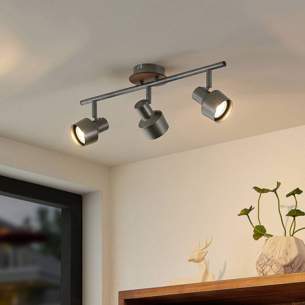 Dreiflammiger Deckenstrahler im Industrial-Design aus Metall und Holz, montiert über einem Regal mit Dekoration und Zimmerpflanze.